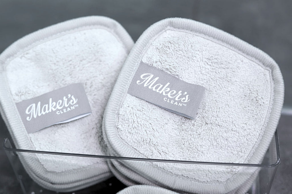 two grey eye makeup remover pads in a glass dish