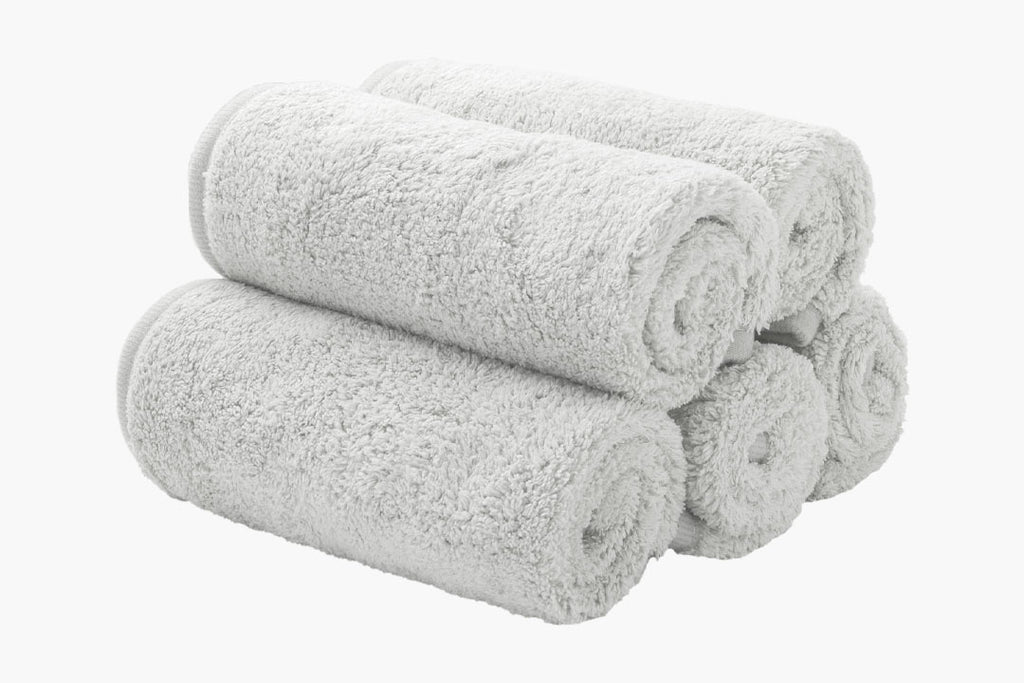 five grey luxury face cloths rolled up and stacked