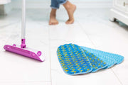 A purple taco-shaped microfiber mop head and four reusable mop pads on a white bathroom floor.